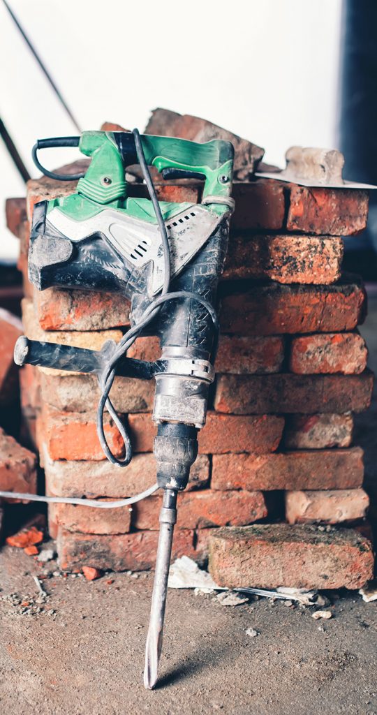 Construction tool, industrial jackhammer with demolition debris and bricks